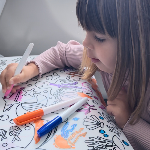 Child using a silicone reusable coloring mat during a family trip.