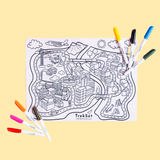 A reusable silicone coloring mat with a 'Busy Town' design laid out flat alongside eight vibrant, non-toxic dry erase markers.