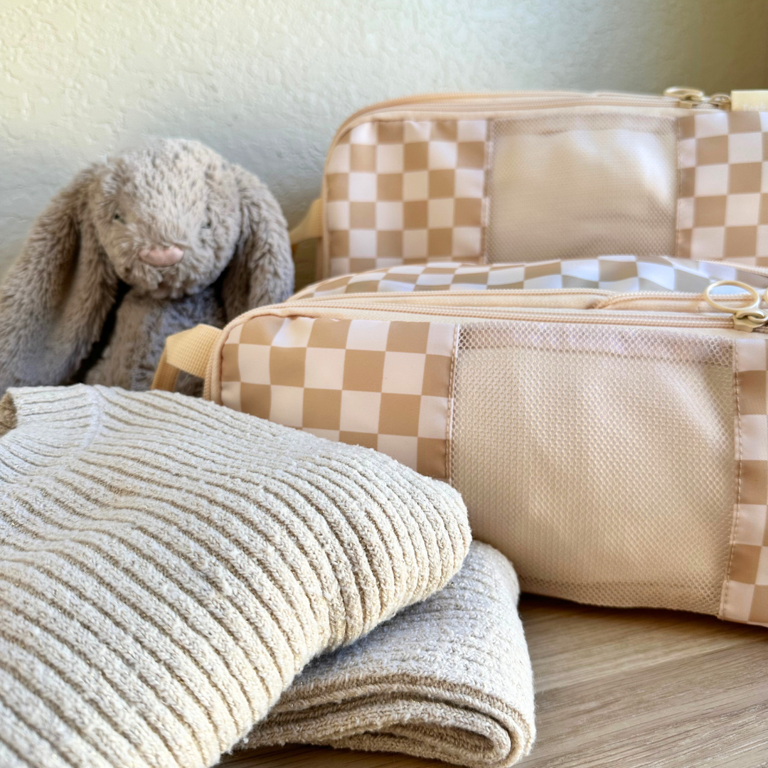 Set of 2 Tan Checkerboard Compression Packing Cubes in a lifestyle setting on a kids dresser