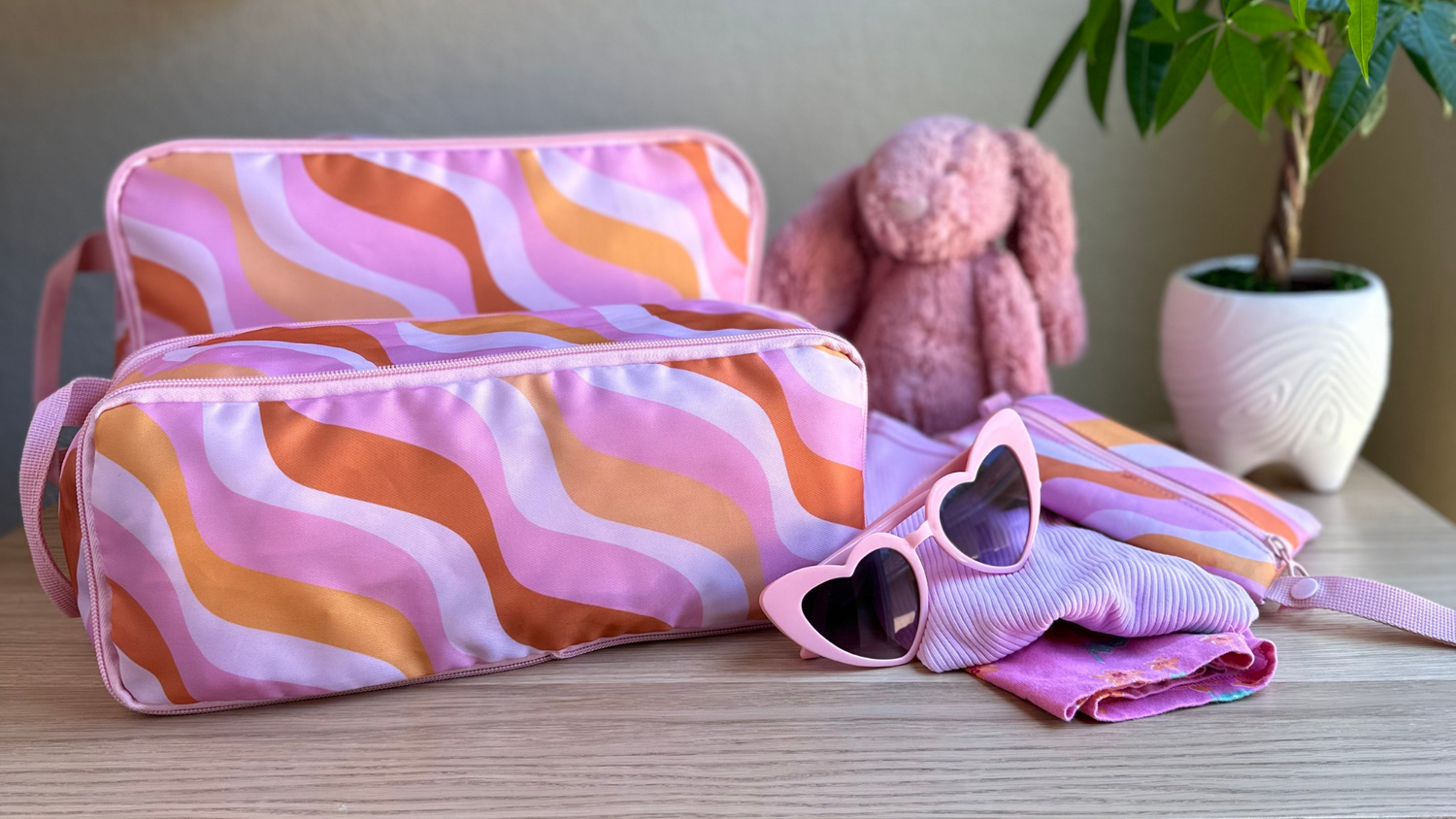 Set of 2 Pink and Orange Wave Compression Packing Cubes with pink girls accessories on top of a childs dresser